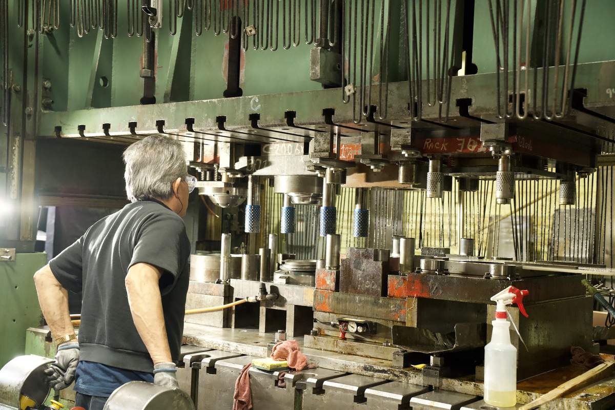 Manor Tool operator running precision stamping press for aerospace component production